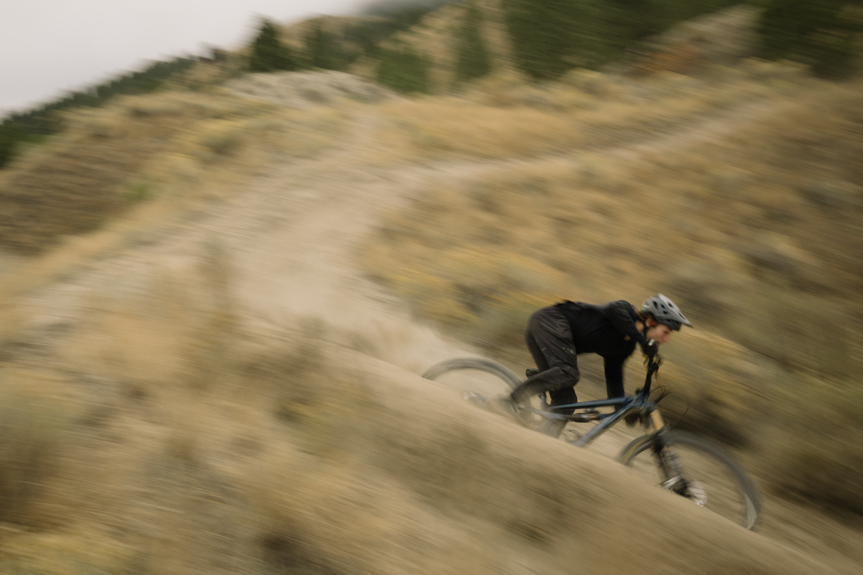 Rider carving a fast loose corner, rear tyre throwing roost